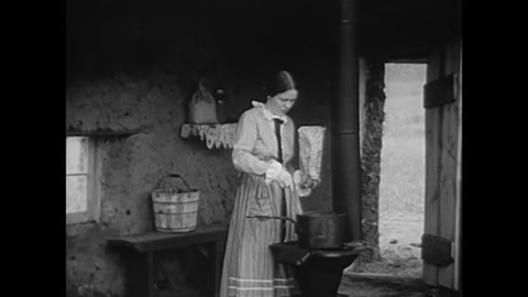 CIRCA 1940s - In a scene from a 1942 film, a pioneer mother starts housekeeping while her children collect buffalo chips for fuel in the 1870s.