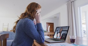 Caucasian woman using laptop and phone headset on video call with female colleague. staying at home in self isolation during quarantine lockdown.