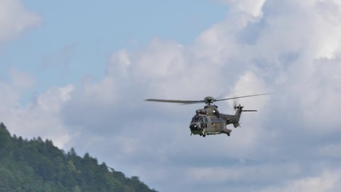 Mollis Switzerland 16 August 2019: Green and brown camouflage military transport helicopter flying at high speed in a mountain valley then climbs vertically and turns back. Airbus Helicopters Cougar