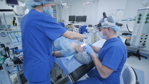 The anesthesiologist with assistant prepares female patient for surgery, puts patient into anesthesia, regulates oxygen mask, endotracheal tube. Surgery. Anesthesia