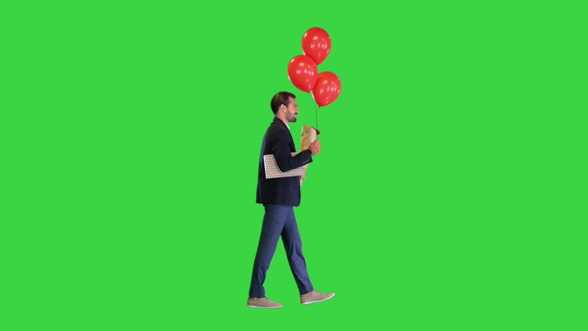 Elegant man, in a suit, with a bouquet of flowers, a gift and balloons walking on a Green Screen, Chroma Key.