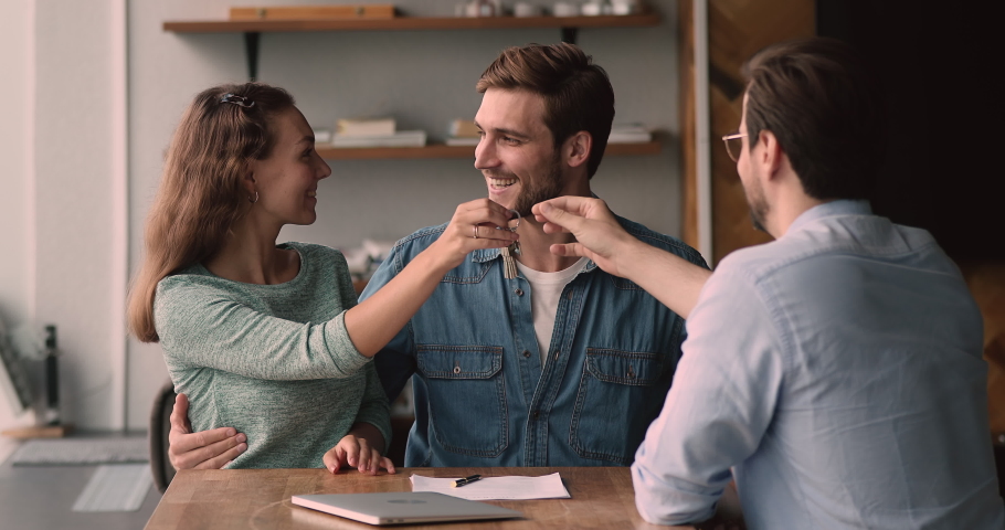 Happy loving family couple discussing apartment purchase with professional real estate agent at office meeting, signing paper contract, getting keys from own accommodation, celebrating successful deal Royalty-Free Stock Footage #1066586338