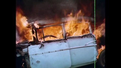 CIRCA 1971 - In this exploitation movie, a man driving away from the cops crashes his car in a ditch and it promptly bursts into flames.