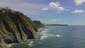 This aerial video features the cliffs of a Costa Rica beach above a blue ocean.