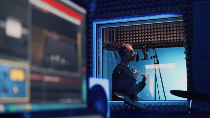 Male Rap Singer with Headphones and Sound Engineer are Creating a New Song in Professional Recording Studio. Program and Tools for Creating Music on Computer Monitor. Work in the Music Recording Room | Shutterstock HD Video #1066597186