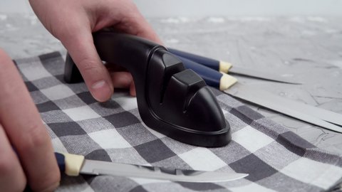 Man manually sharpens kitchen knives. Knife sharpening. The concept of caring for knife sharpness.