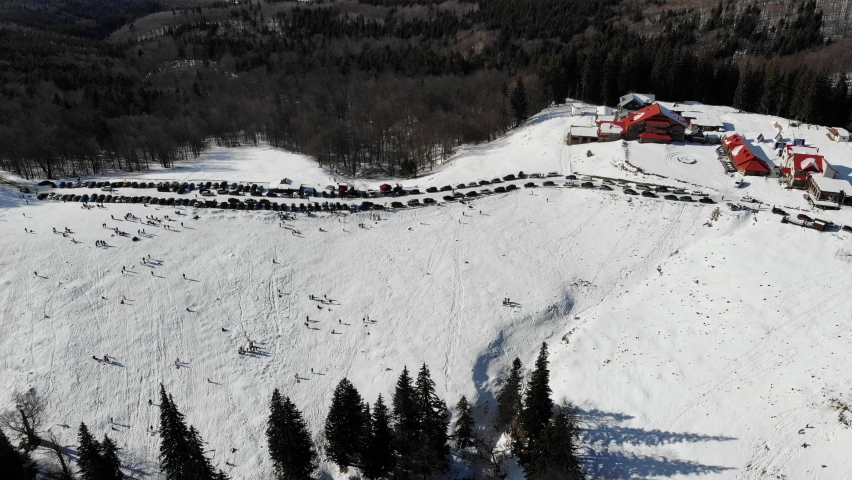 Aerial view of the sleigh slope and the hut with a red roof at the Red Mountain resort in the Carpathians on a sunny winter day