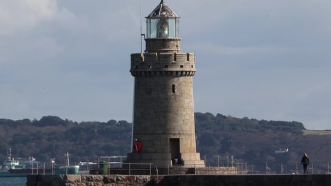 Reveal shot of light house on Castle Breakwater St Peter Port Guernsey with Herm Island in the background.