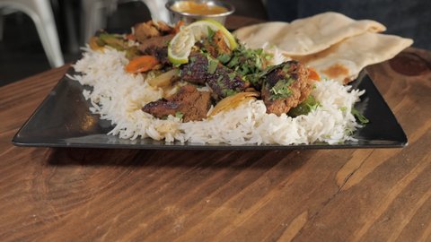 Fork picks up piece of beef tandoori kabob over rice and vegetables, push slider close up 4K