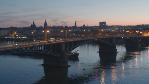 sunset aerial drone shot of city of Mainz by night with a drone over the old bridge and a ship on the rhine river Luftaufnahmen per Drohne
