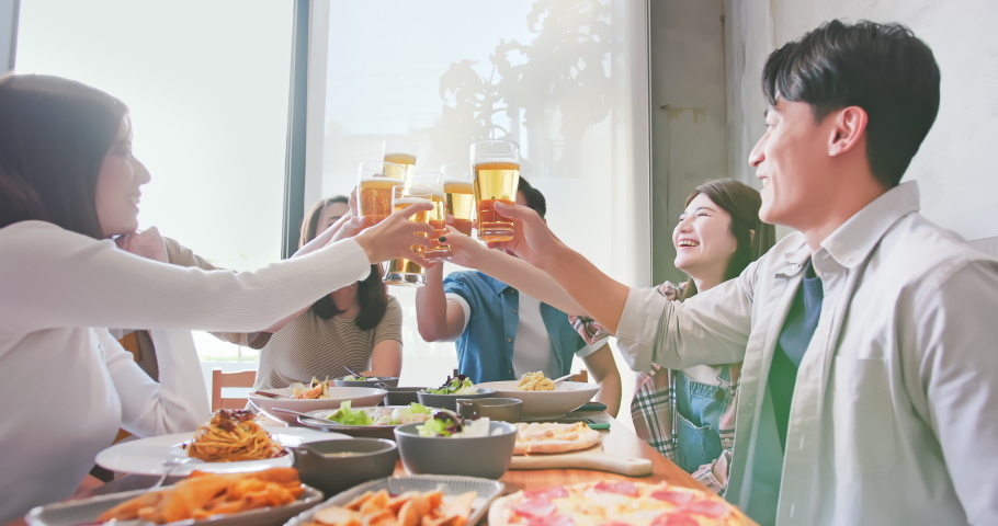 Group of asian happy friends drinking and toasting beer in restaurant