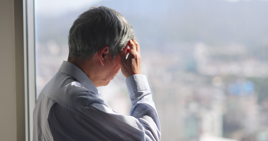 Asian stressed senior businessman standing near a window is worrying about economic downturn in future of the company in office | Shutterstock HD Video #1066606732
