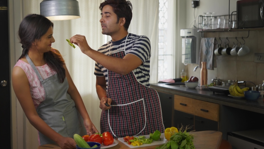 shot of a young attractive and happy Indian husband helping wife to prepare food for dinner or chop vegetables in the kitchen, a couple having quality time together while cooking a meal on holidays Royalty-Free Stock Footage #1066613581