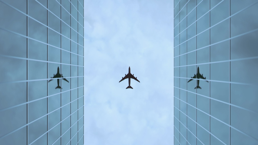 An airplane flies over two glass skyscrapers with reflective windows as seen from below Royalty-Free Stock Footage #1066618078