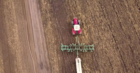 Aerial view of a tractor pulling a plow and an anhydrous tank of ammonia in a farmer's field. Heavy machinery during cultivation, work in the fields. Agricultural tractor in the field.