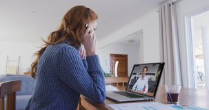 Caucasian woman using laptop and phone headset on video call with male colleague. staying at home in self isolation during quarantine lockdown.
