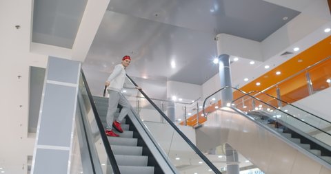 Young man breakdancing on escalator in shopping mall. Professional dancer making hip hop movements in moving staircase in business center