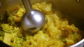 Cooking vegetable soup with broccoli, cauliflower, potatoes puree with a hand blender.