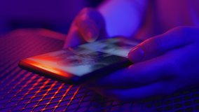 Use of mobile phone in shining neon light. Creative vivid color of ultraviolet red and blue. Hands of woman scroll up photos of instagram app. Social media photography closeup at party in night club - Powered by Shutterstock - Get 15% off with code: PIKWIZARD15
