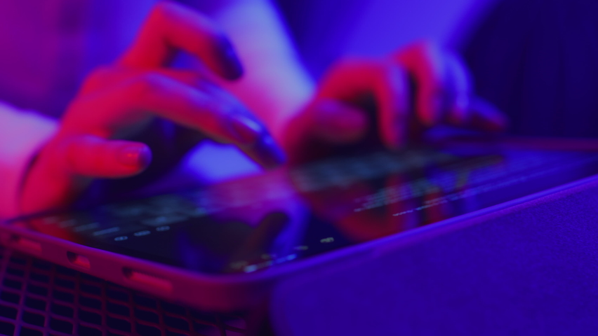 Use of tablet pc in shining neon light. Creative vivid color of ultraviolet red and blue. Hands of person typing article text or document on mobile computer closeup in trendy neon room at dark night Royalty-Free Stock Footage #1066645480