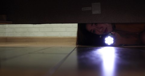 Asian woman with a flashlight looking lost item under the sofa, Error or Not found concept