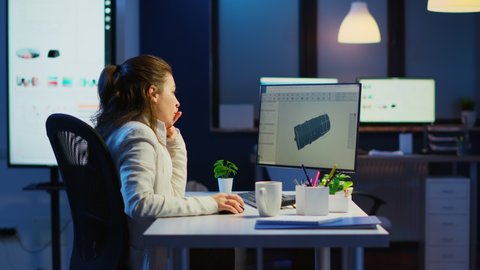 Tired designer engineer analizing new prototype of 3D model of the plant yawning working overtime. Industrial female worker studying turbine idea on pc showing cad software on device display