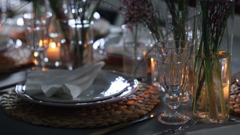 A beautifully decorated table set for a festive candlelit dinner. Glasses, lens flare and dark background. Light from candles. Dinner in the dark.
