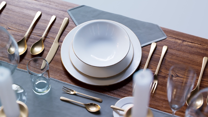 Seamless loop animation of elegant tableware at a restaurant. Dinner set at the wedding reception. Plates, glasses, candles and gold flatware on the wooden table. Ready for a big dinner. Celebration. | Shutterstock HD Video #1066661293