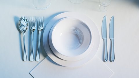 Animation of elegant tableware at the restaurant. Dinner set at the wedding reception. Plates, forks, spoon and glasses on the white tablecloth. Table ready for a big dinner. Closeup.Celebration time