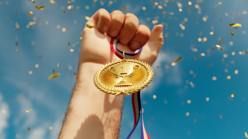 Rising hand holding a shiny gold medal. Top winner with first prize. Sports award for a champion. Winning a competition. Success, victory, triumph. Moment of glory. The greatest achievement. Confetti. Royalty-Free Stock Footage #1066662865