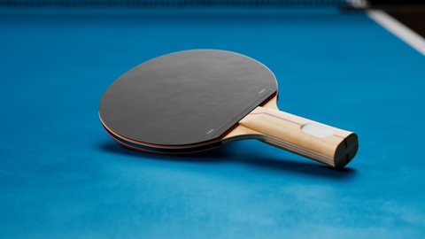 The camera is focusing on a table tennis bat and zooming-out. The aerial view on the table with paddles, ball, and net. Professional ping pong equipment ready to play. In the middle of the competition