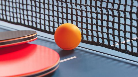 The camera is moving around a table tennis ball. Ping pong ball, paddles and net. Ping pong accessories ready to play. Professional sports equipment for table tennis. In the middle of the competition