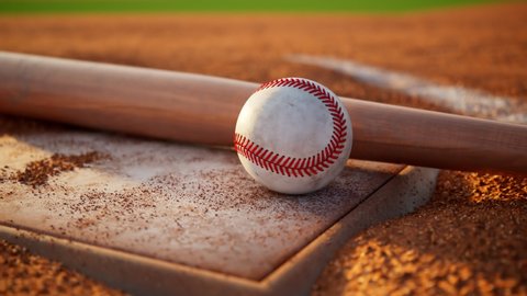 Baseball home plate with baseball and bat. Home base with baseball accessories. Camera moving around sports gear. Beautiful soft warm light. Brake in a game. Major League Baseball. American sport