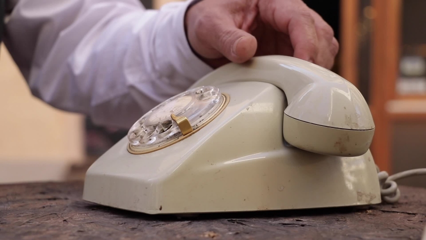 Close-up view of a hand picking up the telephone receiver and dialing two numbers on an old rotary phone. Royalty-Free Stock Footage #1066669891