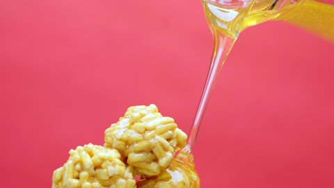 Pouring fresh honey on traditional Tatar sweets chack-chack from glass jug on pink background extreme close view