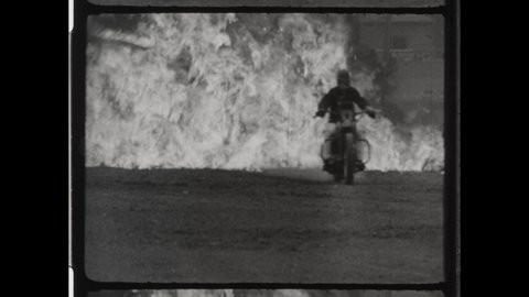 1940s Indianapolis, IN. Motorcycle Stuntman Drives through Fire. The Daredevil burst through Wall of Flames at a High rate of Speed. 4K Overscan of Vintage Archival 16mm Film Print. 