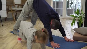 Father and little daughter do yoga together at home in the living room. Coronavirus lockdown and stay-at-home order. Covid-19 and healthy body lifestyle concept - Powered by Shutterstock - Get 15% off with code: PIKWIZARD15