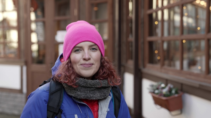 woman is travelling at winter, walking in small town on streets, outdoors portrait