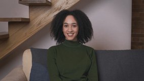 Comfort at home. Close up portrait of young black woman sitting on couch, smiling at camera