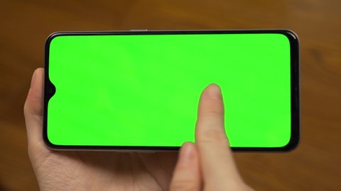 The Woman's Hand Touches Flips Slides  Drags on a Green Background, Green Screen of a Horizontal Mobile Phone on a Green Background, Green Screen, Mock up, Uses the Smartphone: stockvideo