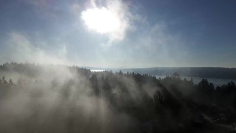 Wisps of lingering fog burn away as the sun reveals panoramic Puget Sound and Mount Rainier, aerial
