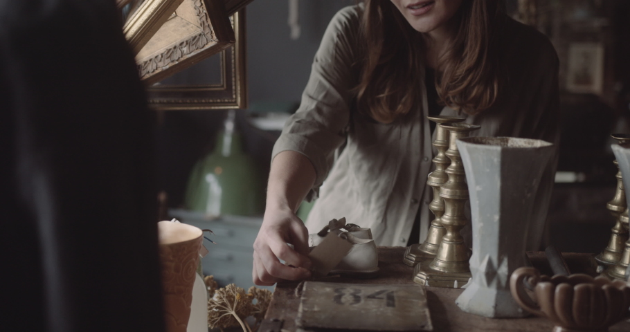 Young adult female browsing vintage store looking at price label