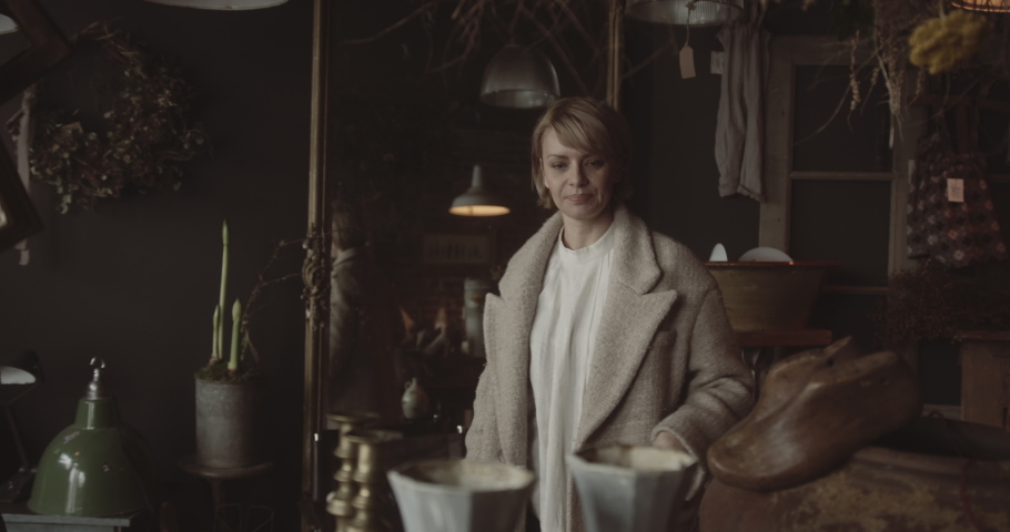 Retail shop owner advising customer in antique store on vase purchase