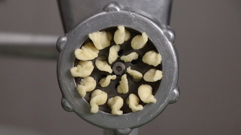 chef rotating vintage metal meat grinder close-up. the dough is squeezed out through the holes