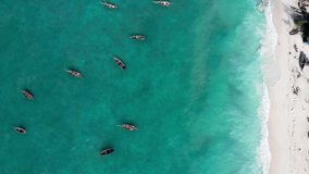 Aerial shot of the fisherman's boat floating on turquoise Indian ocean waves near the Zanzibar island, Tanzania. Flying drone point view 4K footage. Traveling and fishing industry concept video.