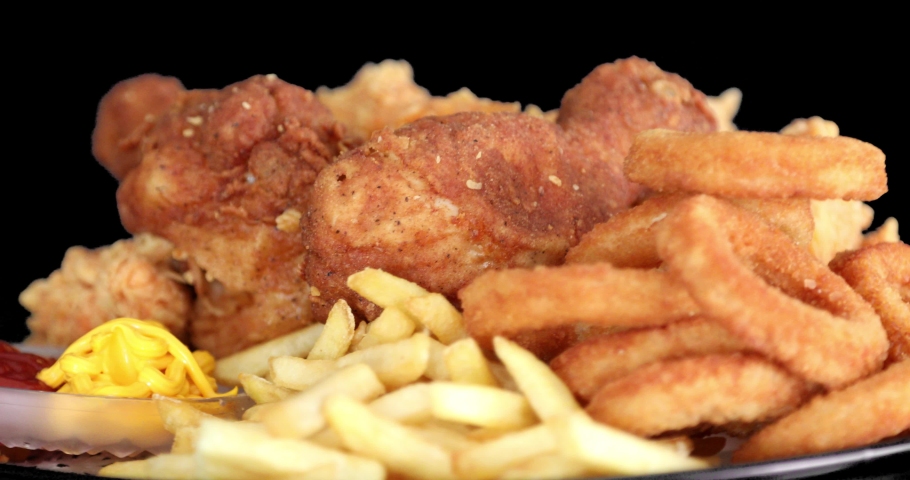 Macro view of Tasty french fries and crispy chicken nuggets with mustard and ketchup at black background