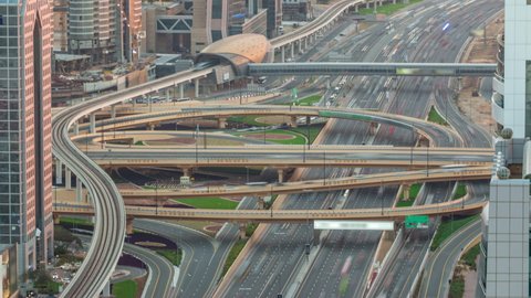 Aerial top view of highway junction with traffic timelapse in Dubai, UAE at sunset. Famous Sheikh Zayed road in Dubai downtown. Transportation and driving concept view from rooftop.