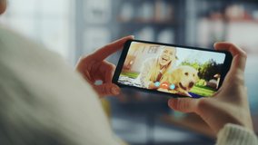 Close Up of a Female Chatting in a Video Call with Her Beautiful Friend Playing with a Dog on Smartphone from Home Living Room. Freelancer Chatting with a Client on a Call Over the Internet.