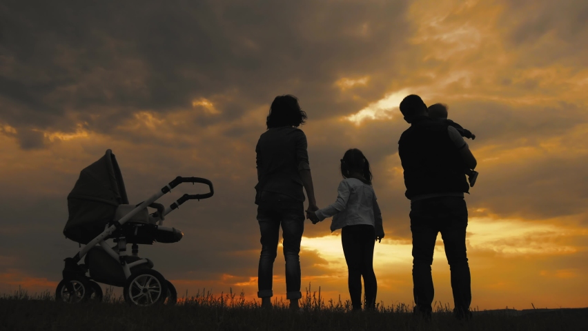 Silhouettes of happy parents having good time with their little children on park. Happy family silhouette walk at sunset. | Shutterstock HD Video #1066707688