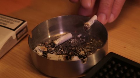 Man in a bar putting out a cigarette in an ashtray